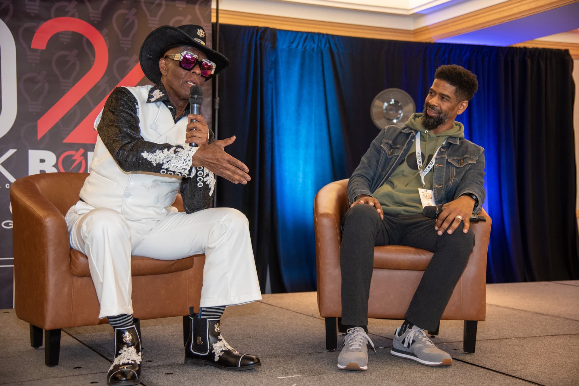 Troy on the festival stage in conversation with a guest seated in an armchair beside him